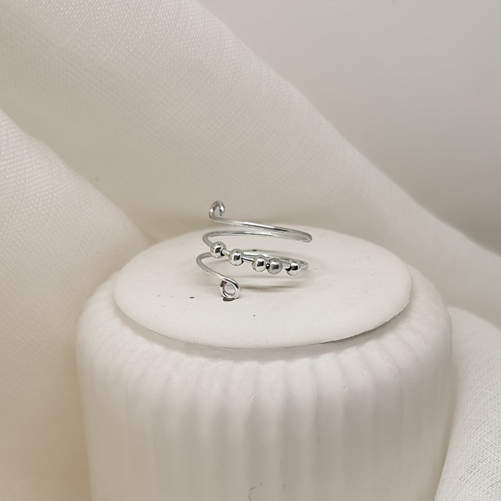 Handgefertigter, minimalistischer Silberring für Damen, edles Schmuckfoto auf hellem Podest, moderner Clean-Girl-Look.