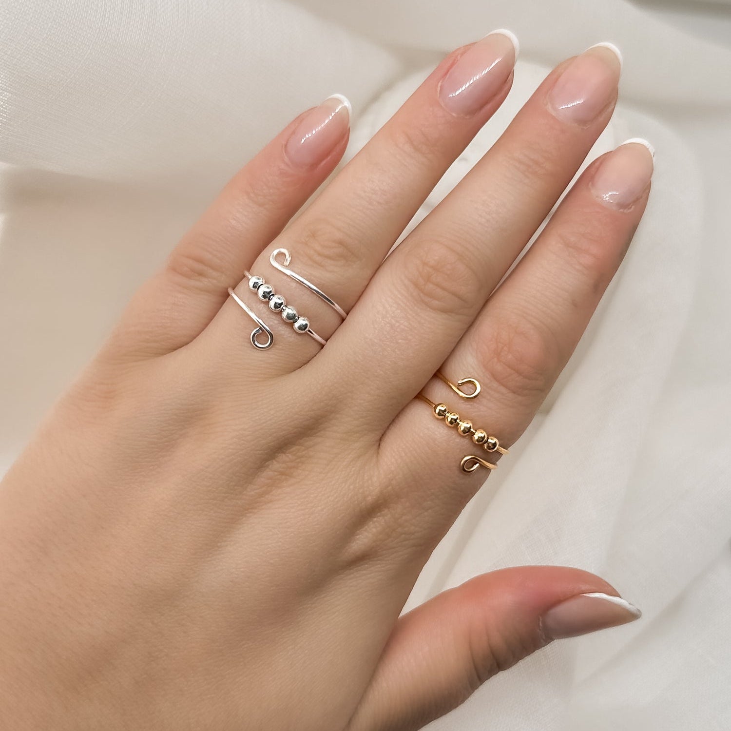Handgemachte Damenringe aus Silber und Gold, getragen an einer Damenhand, minimalistisches Schmuckdesign, edles Produktfoto im Clean-Girl-Stil.