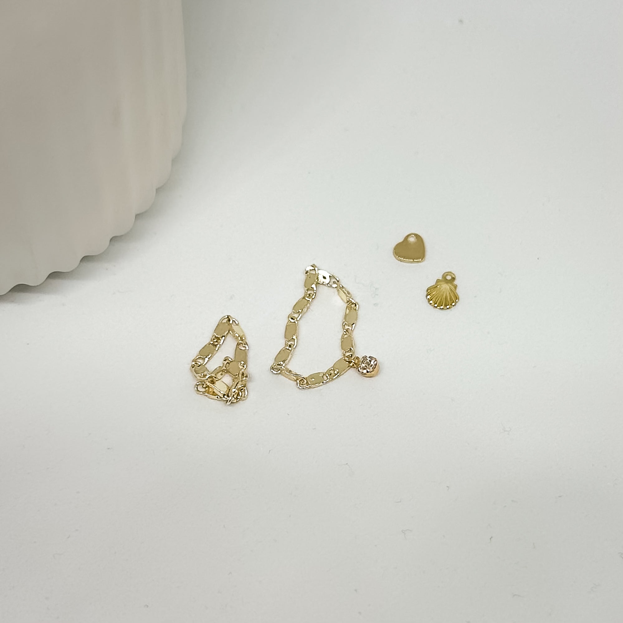 goldene Ringe und kleine Charms lose auf weißem Hintergrund – minimalistischer Goldschmuck
