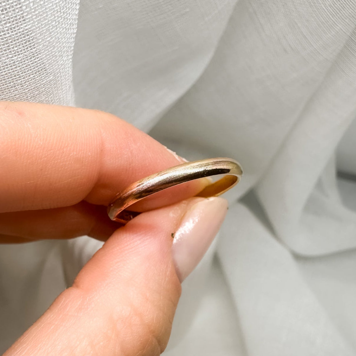 Goldfarbener Ring zwischen Fingern – Detailaufnahme