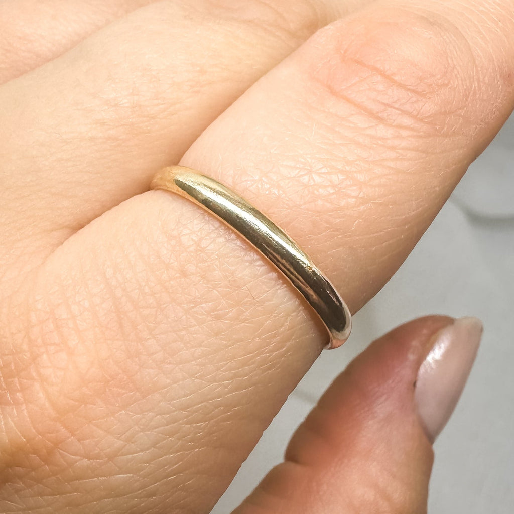 Schlichter goldfarbener Ring an Hand auf weißem Hintergrund – minimalistisch