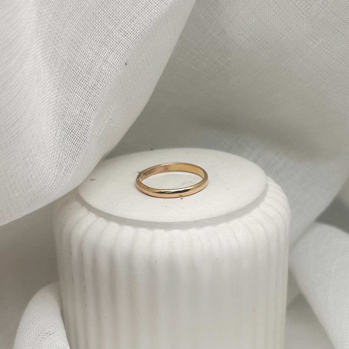 Minimalistischer goldfarbener Ring auf weißer Dose – Produktfoto