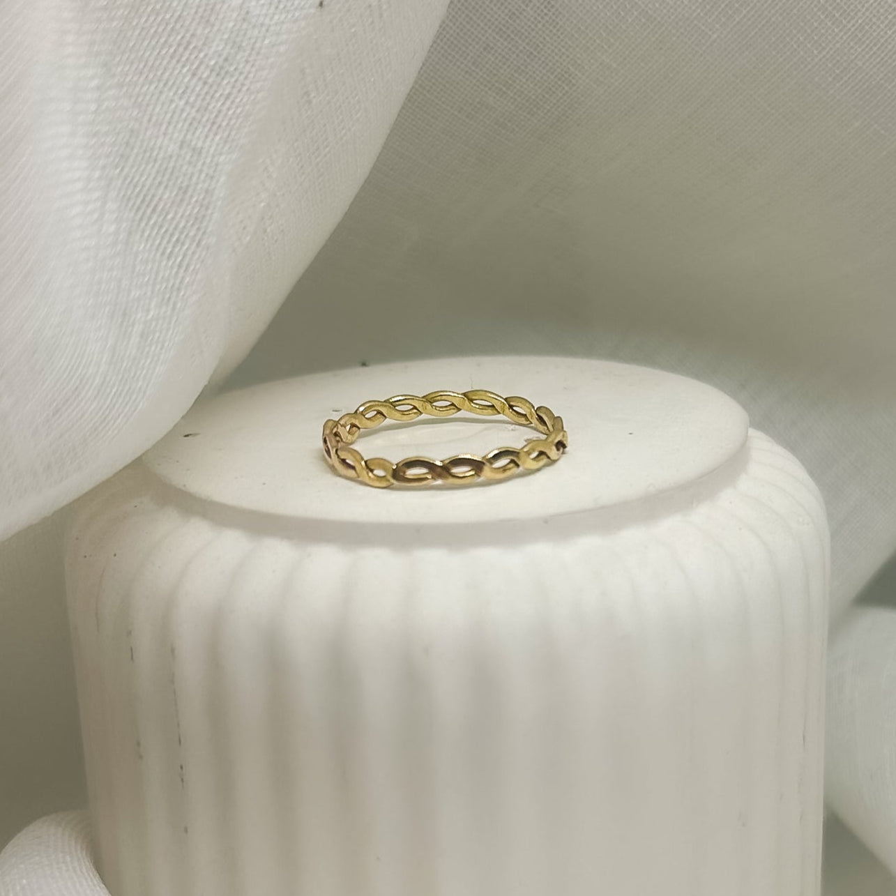 Filigraner Messingring mit gedrehter Kettenoptik auf weißem Stoffhintergrund – minimalistischer Schmuck