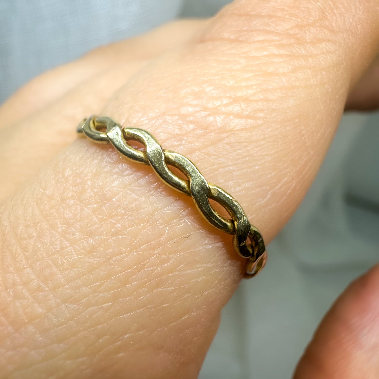 Nahaufnahme eines gedrehten Messingrings am Finger – eleganter minimalistischer Schmuck