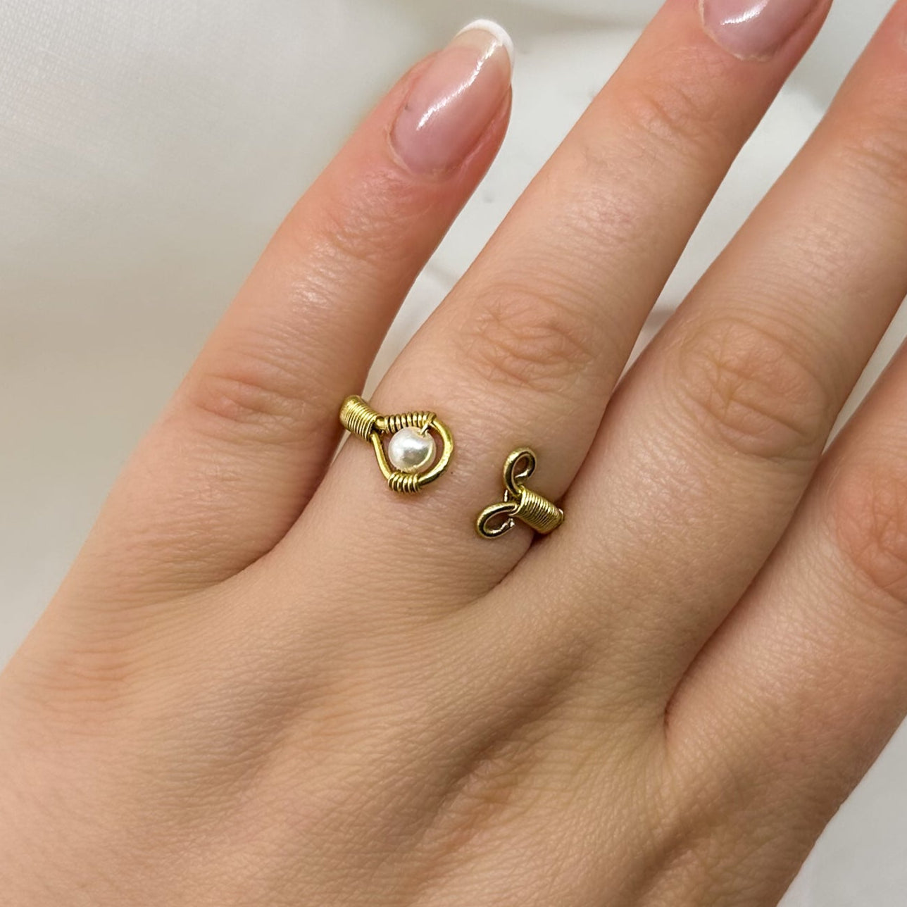 Minimalistischer offener Goldring mit Perle, stilvoll am Finger getragen