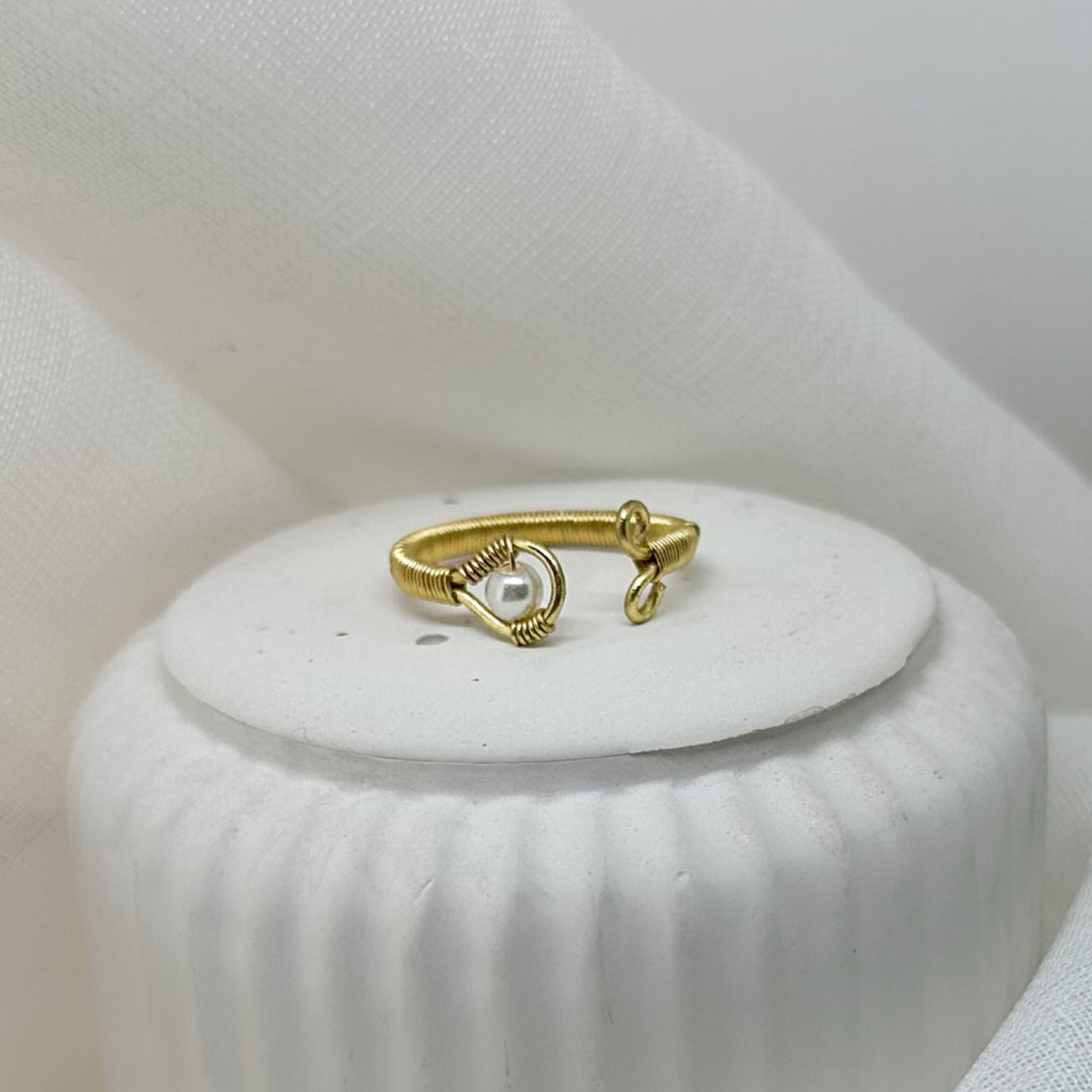 ffener Goldring mit Perle auf weißem Podest – eleganter Minimalismus