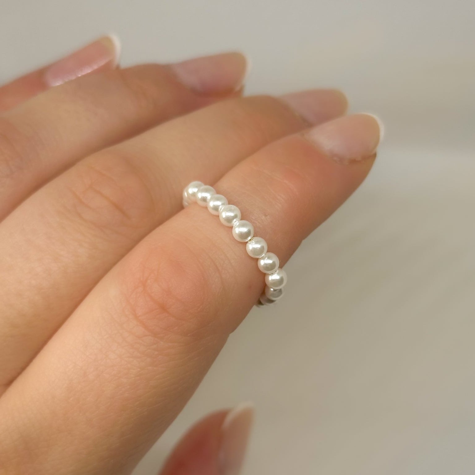 Minimalistischer Perlenring aus weißen Glasperlen ohne Zwischenelemente, getragen an einer Hand, eleganter Schmuck für Alltag und besondere Anlässe.