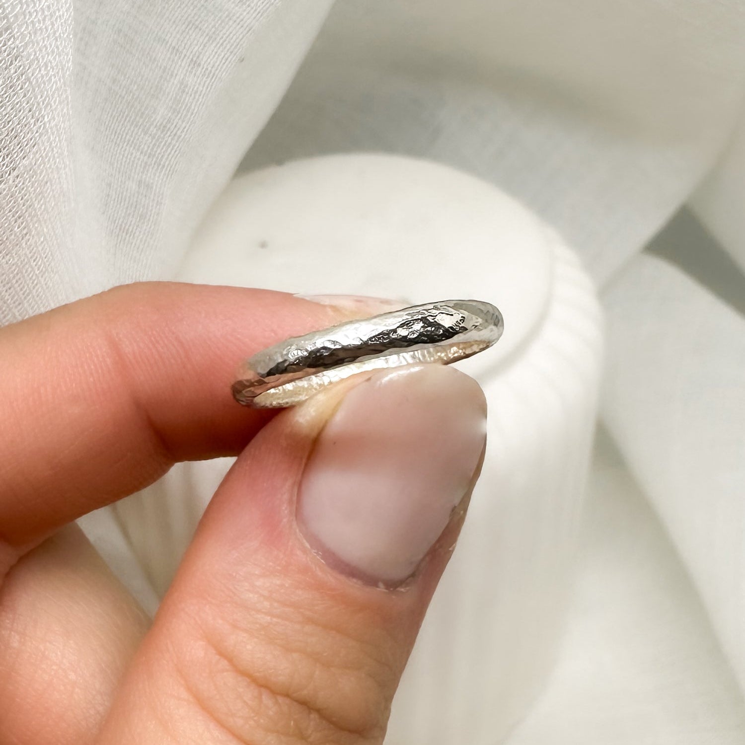 Schlichter Silberring in Hand gehalten vor weißem Hintergrund